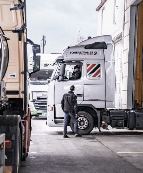 Fahrer im Schwarzmüller-LKW spricht mit Werkstattmitarbeiter – Umsetzung förderfähiger Maßnahmen vor Ort